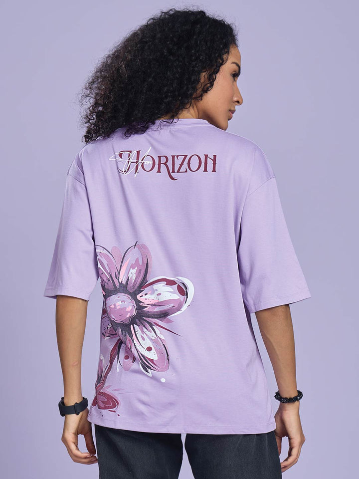 Person wearing a light purple t-shirt with a flower design and 'Horizon' text on the back against a gray background