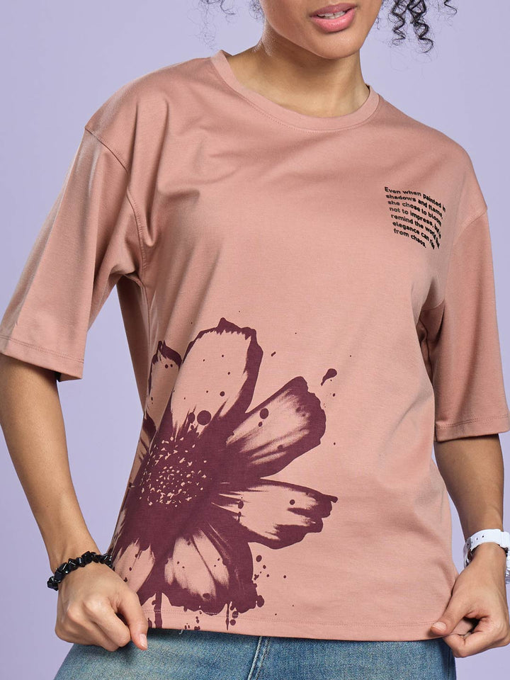 Person wearing a pink t-shirt with a large purple flower design on a light purple background